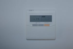 A stylized text-based illustration of a digital thermostat displaying the time 3:48 PM, with buttons labeled 'SET TEMP' and 'START/STOP', set against a background with abstract cloud and topographic line patterns