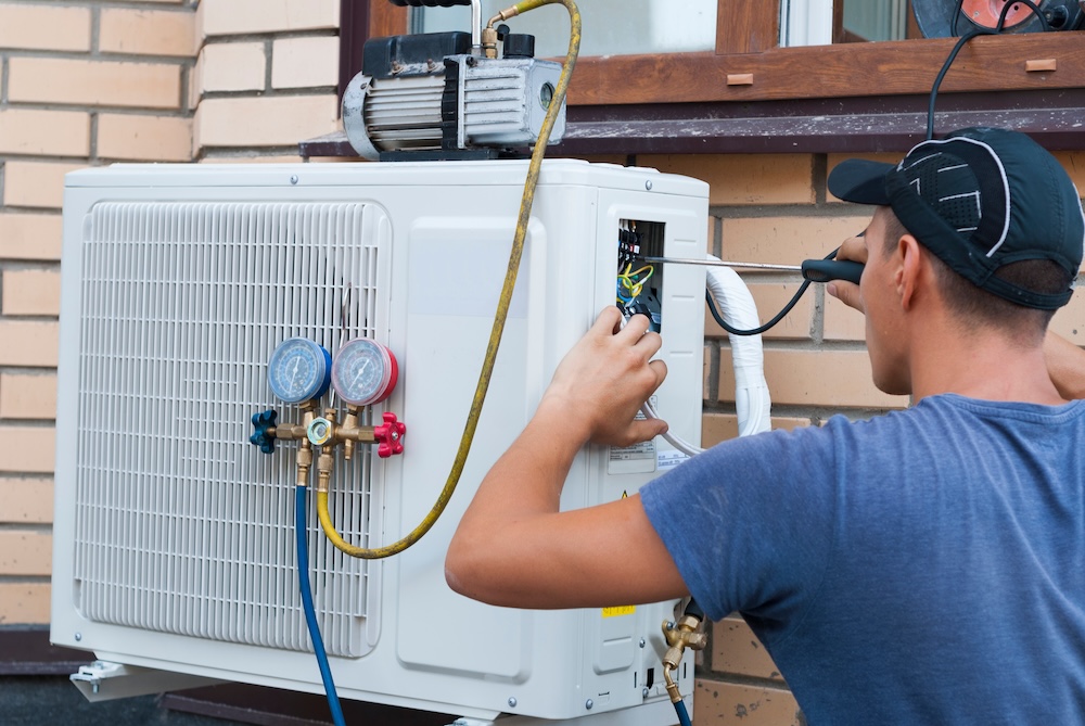 Technician installing a new heat pump system on the side of a residential home in Surrey, BC for efficient climate control