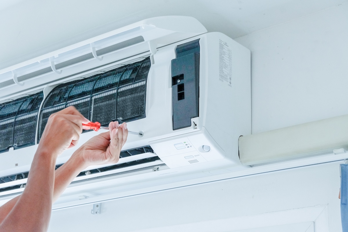 Technician fixing air conditioning unit on the wall. Professional AC service in Vancouver